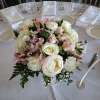 Round centerpiece of pale pink and white flowers on a set dining table