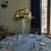 Tall floral centerpiece in a clear glass vase on a set dining table
