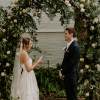 Bride and groom standing beneath a floral wedding arch