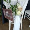 White chair with a floral arrangement and a wooden "Better" sign