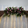 Floral garland with pink and burgundy roses on a wooden arch