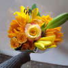 Yellow and orange bouquet with roses and lilies wrapped in clear plastic