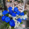 Bouquet of vivid blue roses with white filler flowers and greenery