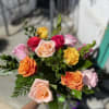 Handheld bouquet of multicolored roses with greenery
