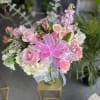 Pink rose bouquet with white flowers and a bright ribbon in a glass vase