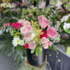 Pink roses and mixed blooms arranged in a black hatbox
