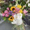 Mixed bouquet with roses, sunflowers, orchids, and lilies in a white vase