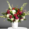Mixed bouquet of red, pink, and white flowers in a white vase