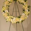 Large floral wreath on a black easel with white and pale yellow flowers