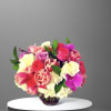 Mixed bouquet of roses, tulips, and orchids in a glass vase