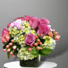 Pink roses and hydrangeas arranged in a dark glass vase
