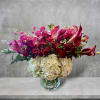 Bouquet of pink calla lilies, red roses, and white hydrangeas in a glass vase