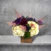 Purple and cream floral arrangement in a wooden square vase