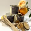 Three candles with an orange rose and citrus fruit accents