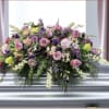 Large pink and purple floral casket spray on a silver casket