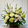 White and pale green floral arrangement in a wicker basket