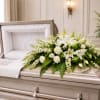 White floral casket spray with lilies and roses on a silver casket