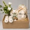 Gift basket with white flowers, a plush bunny, baby booties, and a wrapped item
