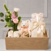 Gift basket with a small flower arrangement, baby clothes, and a plush bunny