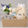 Gift basket with white and blue flowers, baby socks, a teddy bear, and baby items