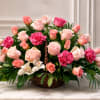 Pink and peach roses arranged in a woven basket with white orchids