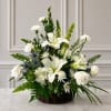 White lilies and carnations in a wicker basket with mixed greenery