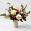 Mixed bouquet of white, cream, pink, and purple flowers in a white vase