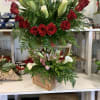 Two floral arrangements with red roses, lilies, and calla lilies in wooden boxes