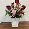 Mixed bouquet of red roses, pink carnations, and lilies in a white gift box