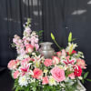 Pink and white floral arrangement around a silver urn