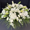 White floral casket spray with roses, lilies, and hydrangeas