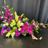 Magenta orchids and pale lilies arranged low on a black surface