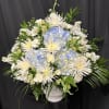 White and pale blue floral arrangement in a white vase