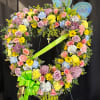 Heart-shaped floral wreath with pastel flowers and a green ribbon