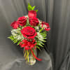 Red roses in a clear glass vase with a red ribbon bow