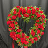 Heart-shaped red rose and carnation wreath on a stand with a red ribbon