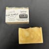 Bar of handmade soap in a labeled wrapper beside an unwrapped soap bar