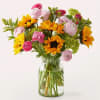 Bouquet of sunflowers and pink ranunculus in a clear glass vase