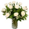 White roses arranged in a clear glass vase with fern foliage