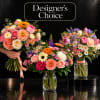 Three colorful mixed flower bouquets in glass vases and one hand-held bouquet