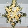 Standing floral spray with yellow roses and white lilies on an easel