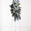 Blue and white funeral spray on a white easel
