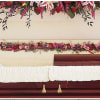 Casket with white drape and red floral sprays