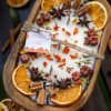 Pumpkin chai candle in a wooden tray with dried orange slices and spices