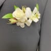 White boutonniere with rose and orchid on a dark suit lapel