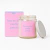 Pink candle jar with a lit wick and matching gift box