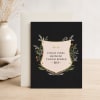 Black greeting card with a motivational quote and floral border, leaning against an envelope