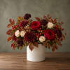 Red roses and burgundy mums in a white vase with autumn berries