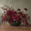 Deep burgundy floral arrangement in a black bowl vase