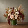 Autumn floral arrangement with blush and white roses in a glass vase